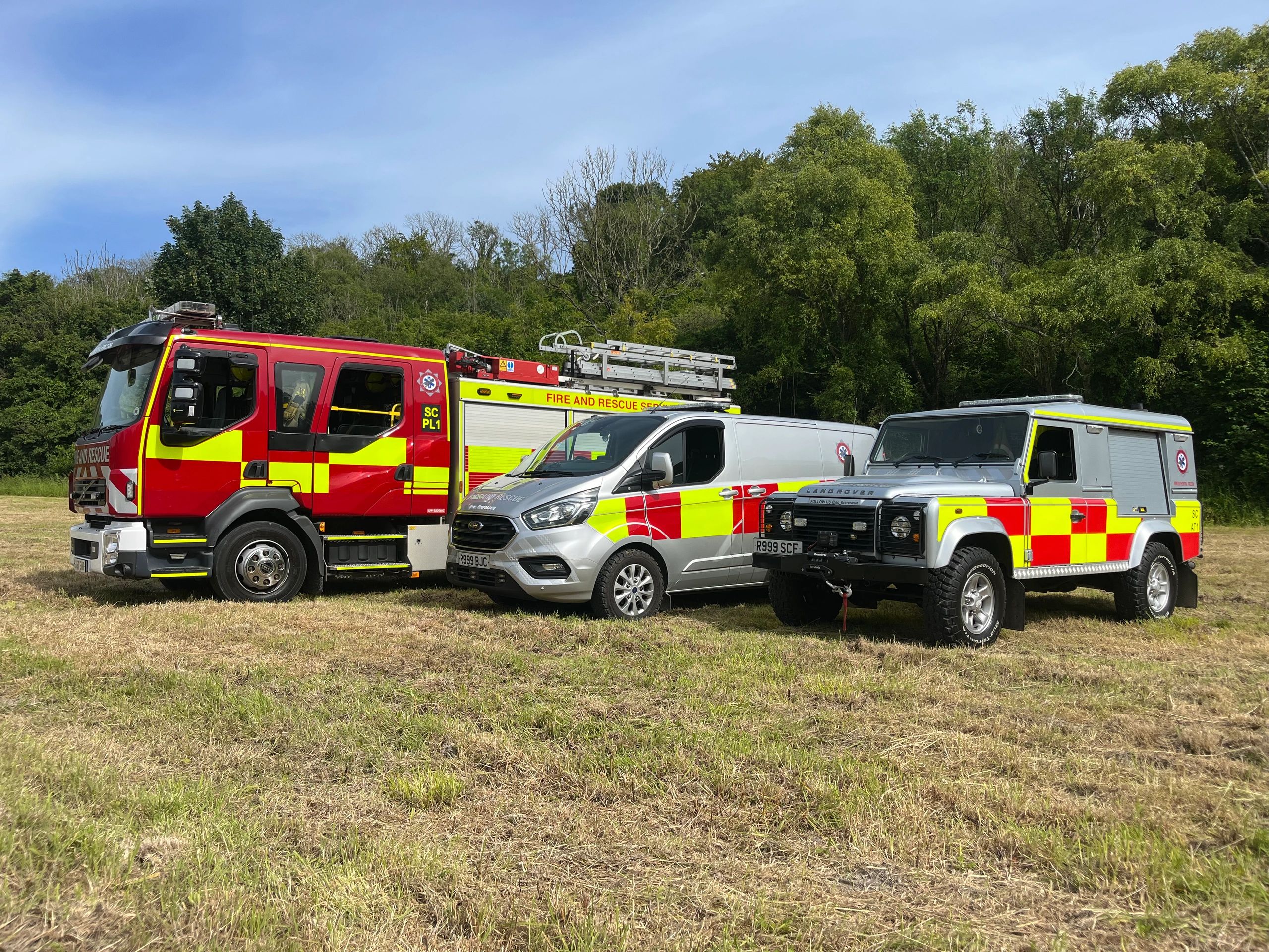 Three south central fire and rescue vehicles parked on grass.