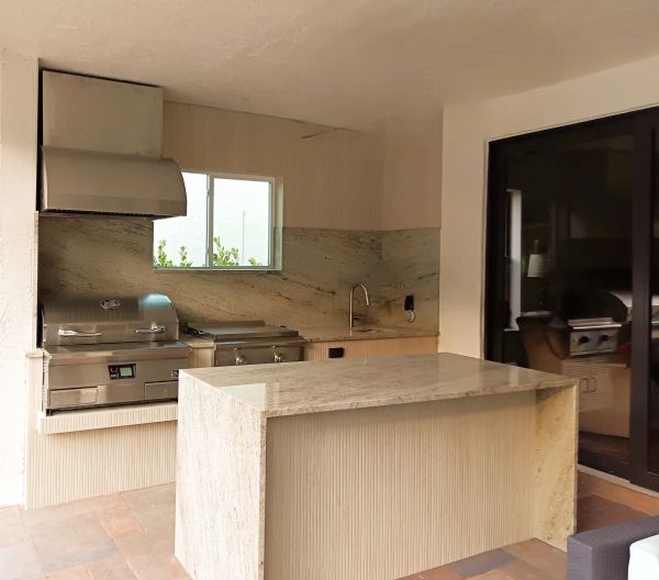 Modern outdoor kitchen with marble countertops and stainless steel appliances.