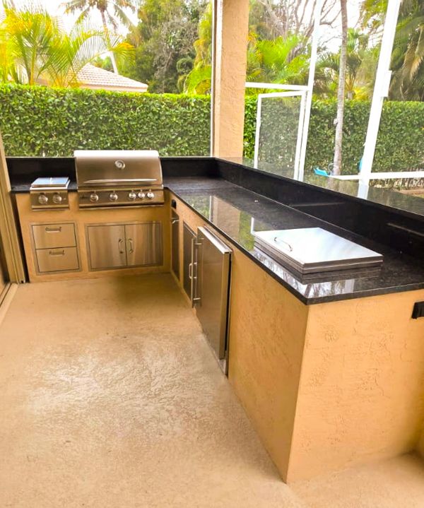 Modern outdoor kitchen with stainless steel grill and black granite countertops.