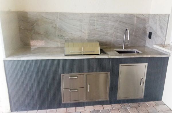 Modern outdoor kitchen with stainless steel grill and sink.
