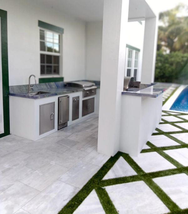 Modern outdoor kitchen with marble countertops and stainless steel appliances.