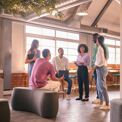 A diverse group of six people in a modern office space, engaged in a collaborative discussion