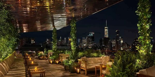 Luxurious rooftop lounge with city skyline view at night.