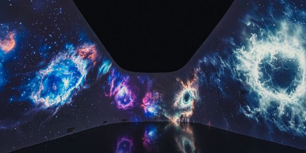 Immersive cosmic nebulae projection in a dark room with reflective floor.