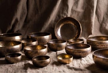 A collection of engraved Tibetan singing bowls arranged on fabric.