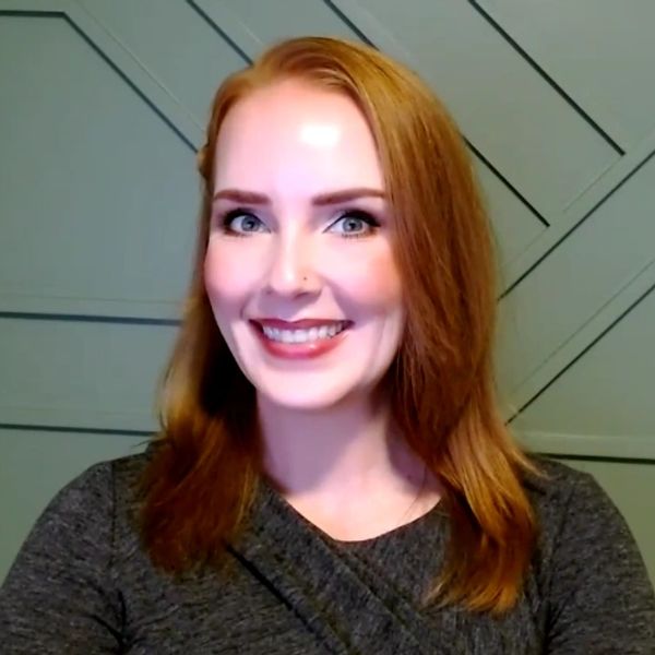 Headshot or Rachel Anderson, white woman in her 40s with red hair in front of a green wall.