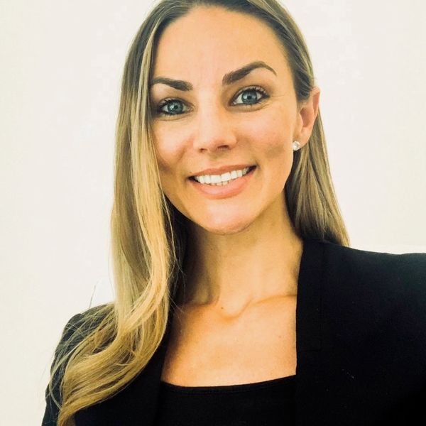 Headshot of Brittny MacIver. A white woman in her 40s with long blonde hair in front of a white back
