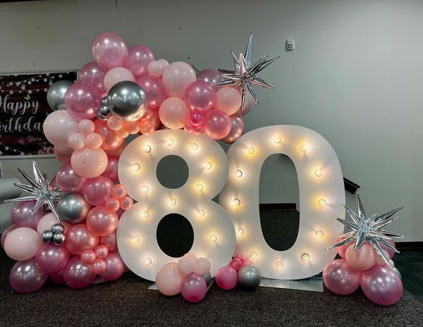 Illuminated '80' birthday display with pink and silver balloons.