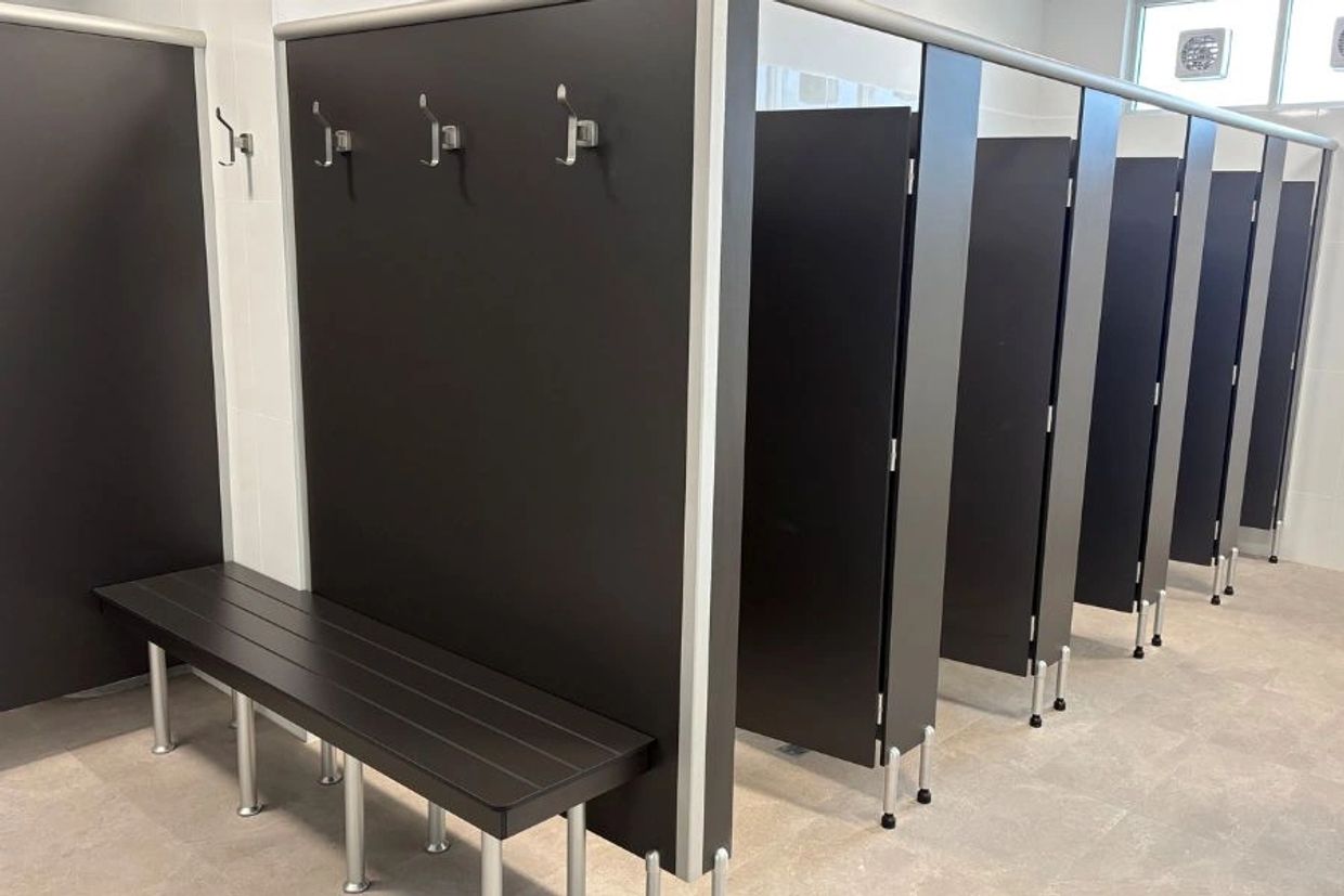 Modern locker room with benches and cubicles.