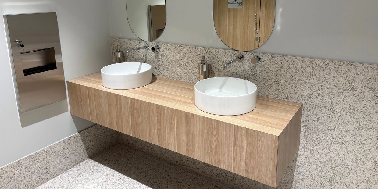 Modern bathroom with wooden floating vanity and round sinks.