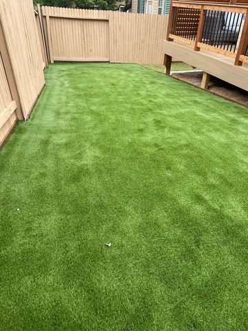 A backyard with freshly installed artificial grass and wooden fencing.