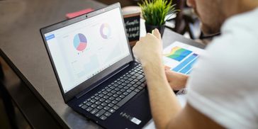 Person sitting infant of a computer looking at piecharts.