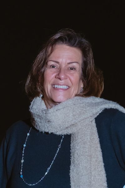 Smiling woman wearing a cozy scarf against a dark background.