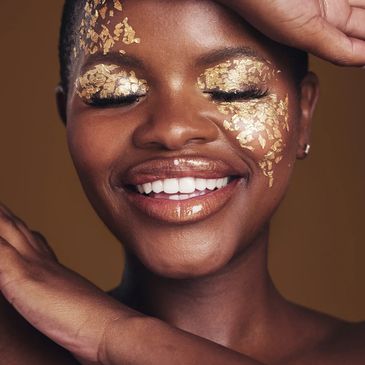 Smiling woman with gold foil makeup on eyes and cheeks.