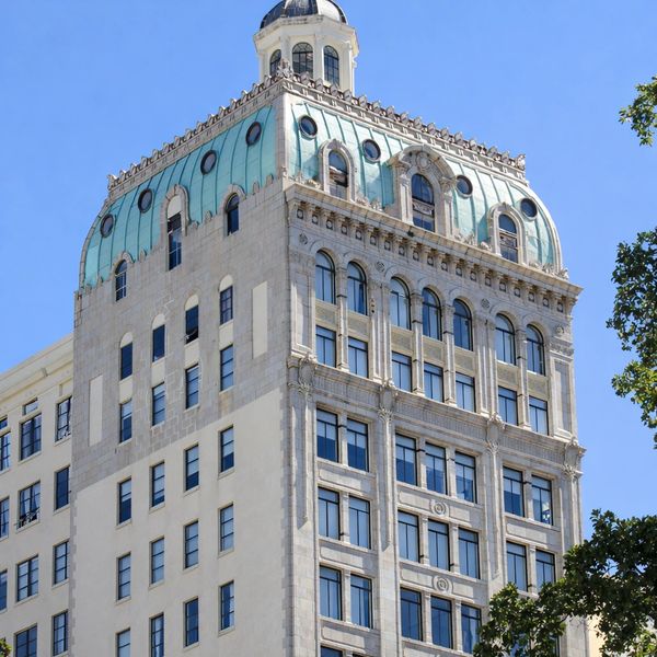 Historic building with a distinctive green copper dome against a clear blue sky.