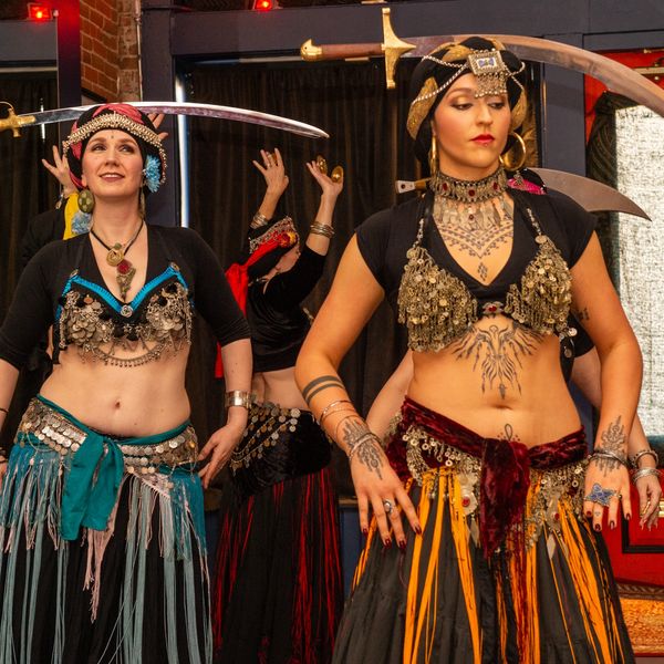 Women performing traditional sword dance in ornate costumes.