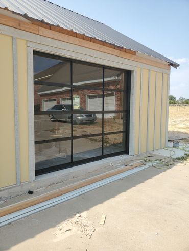 All glass and black metal single frame garage door installation