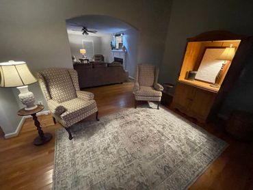 Cozy living area with patterned armchairs, a large rug, and warm lighting.