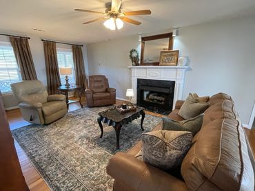 Cozy living room with recliners, a sofa, a fireplace, and a patterned rug.