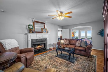 Cozy living room with a fireplace, leather furniture, and a large window view.