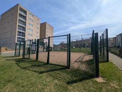Outdoor fenced basketball court near apartment buildings.