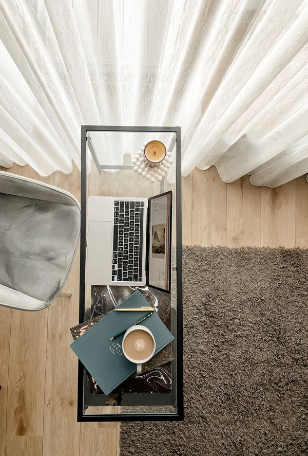 Top view of a cozy workspace with a laptop, coffee, notebook, and candle.