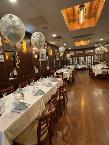 Long Island event balloon decor featuring elegant white and silver helium balloon centerpieces throughout a beautifully set restaurant dining room for a private celebration.