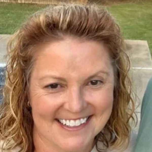 Smiling woman with curly hair outdoors.