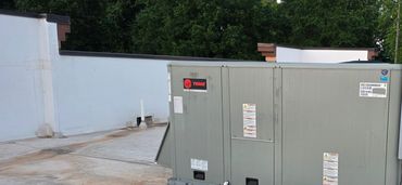 A rooftop HVAC unit with trees in the background.