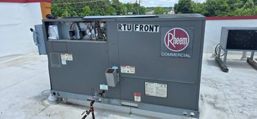 Commercial Rheem RTU unit with open electrical panel on a rooftop.