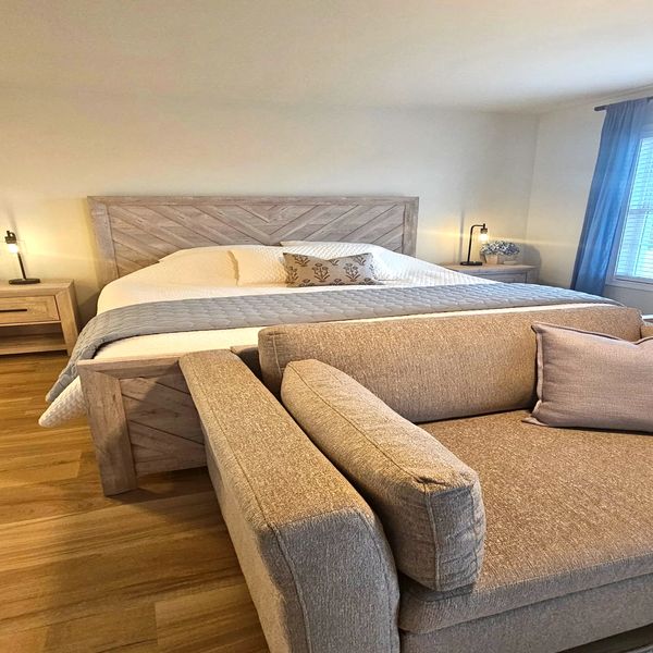 Cozy bedroom with a large bed and a comfortable beige sofa in front.
