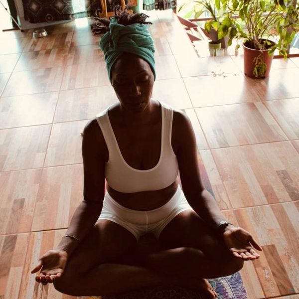 Black Woman sitting cross legged in meditation with palms up
