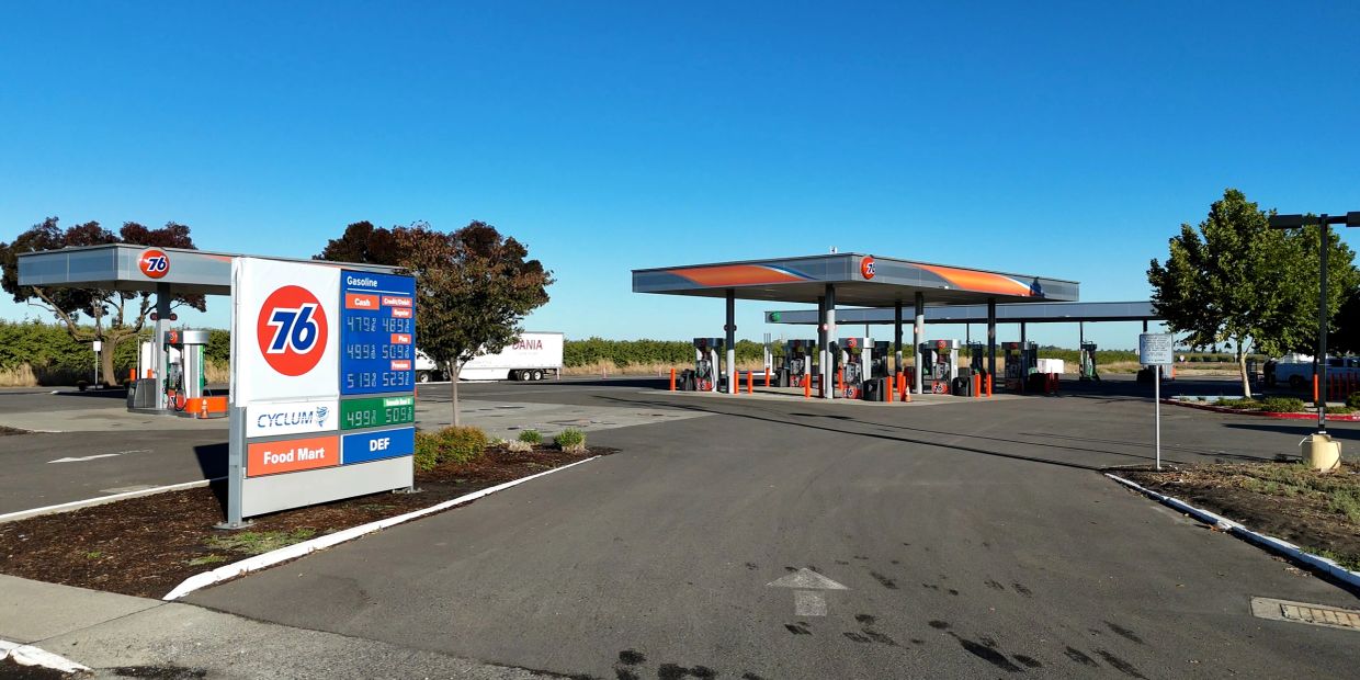 76 gas station with clear blue sky and visible prices.