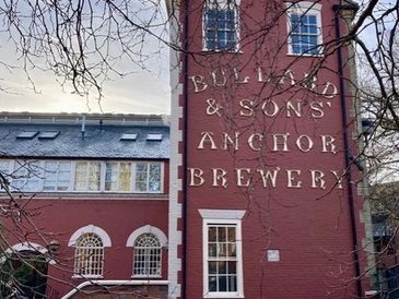 Historic red brick brewery building with large signage.