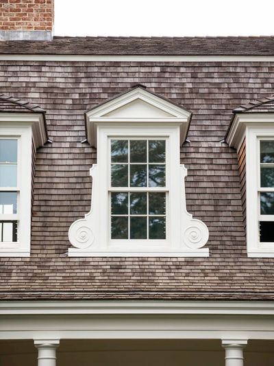 Decorative dormer window with white trim on shingled roof.