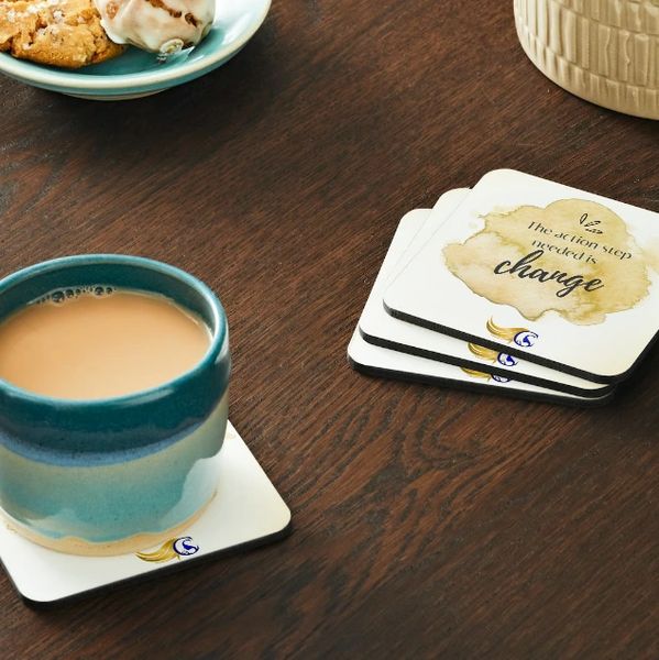 Cup of tea on a coaster with inspirational message coasters nearby.