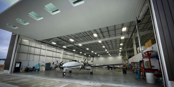 A small twin-engine airplane parked inside a spacious, well-lit hangar.