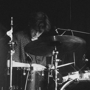 Black and white photo of a drummer playing a Natal drum set on stage.