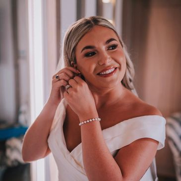 Bride putting in earrings with glamorous makeup and hair
