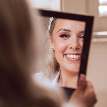 Bride looking at her bridal makeup in mirror
