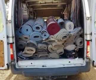 Van loaded with rolled-up carpets or rugs.