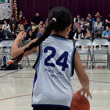 Young basketball player wearing jersey number 24 dribbling the ball during a game.