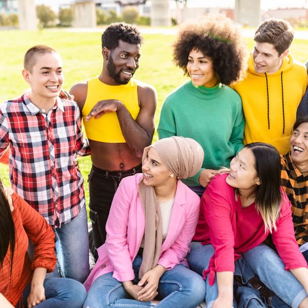 Diverse group of young friends laughing and enjoying time outdoors in a park.