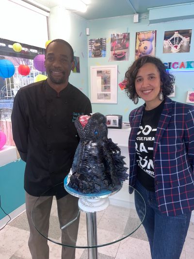 Alt text: Cake designer Damon Nasir, Chef D of ImagiCakes, standing with a smiling customer beside a