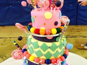 Colorful three-tiered birthday cake with lollipops and candy decorations.