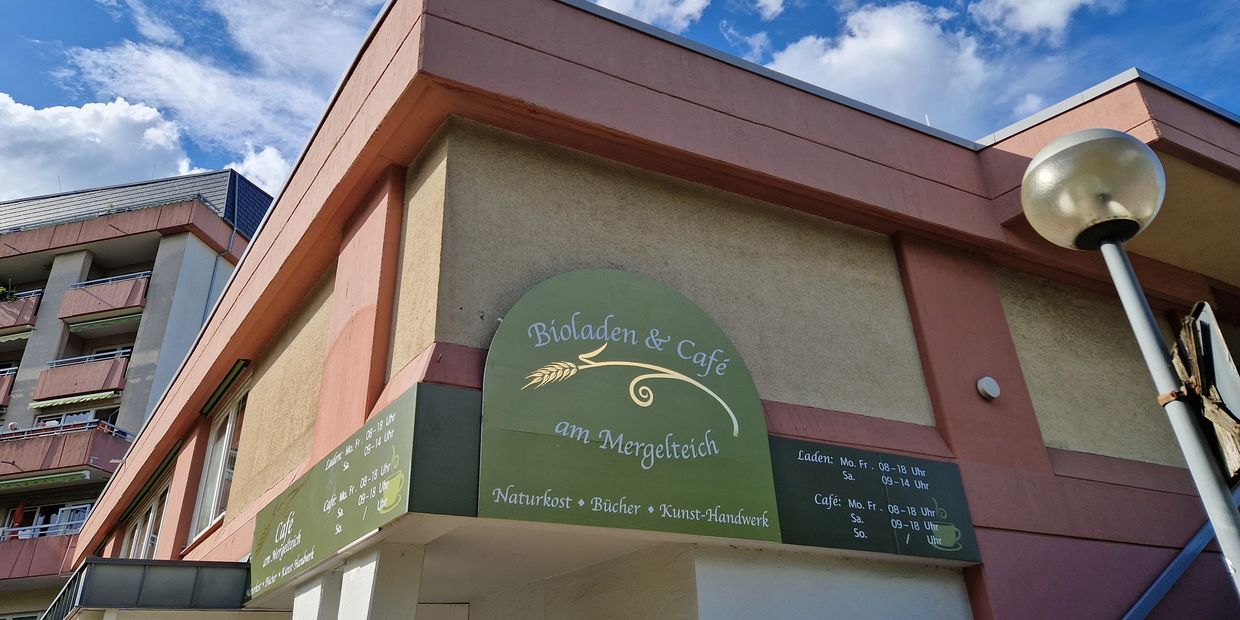 Exterior view of Bioladen & Café am Mergelteich with business hours on display.