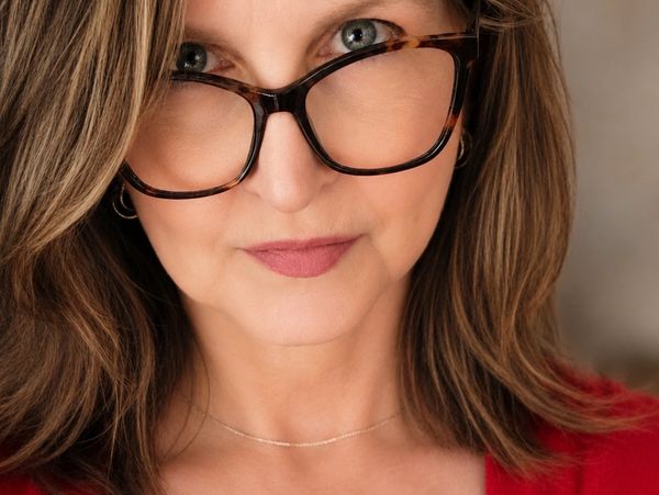 Woman wearing large glasses with light brown hair.