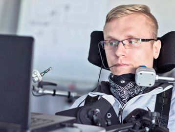 Person using assistive technology works at a computer, focused on the screen.