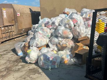 Pile of garbage bags near dumpsters.