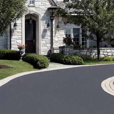 Entrée en asphalte avec tracé courbé et finition soignée réalisée à Laval, intégrée harmonieusement